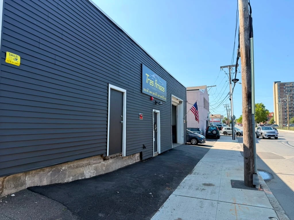 Tres Amigos Auto Body seen from the sidewalk on Commercial St